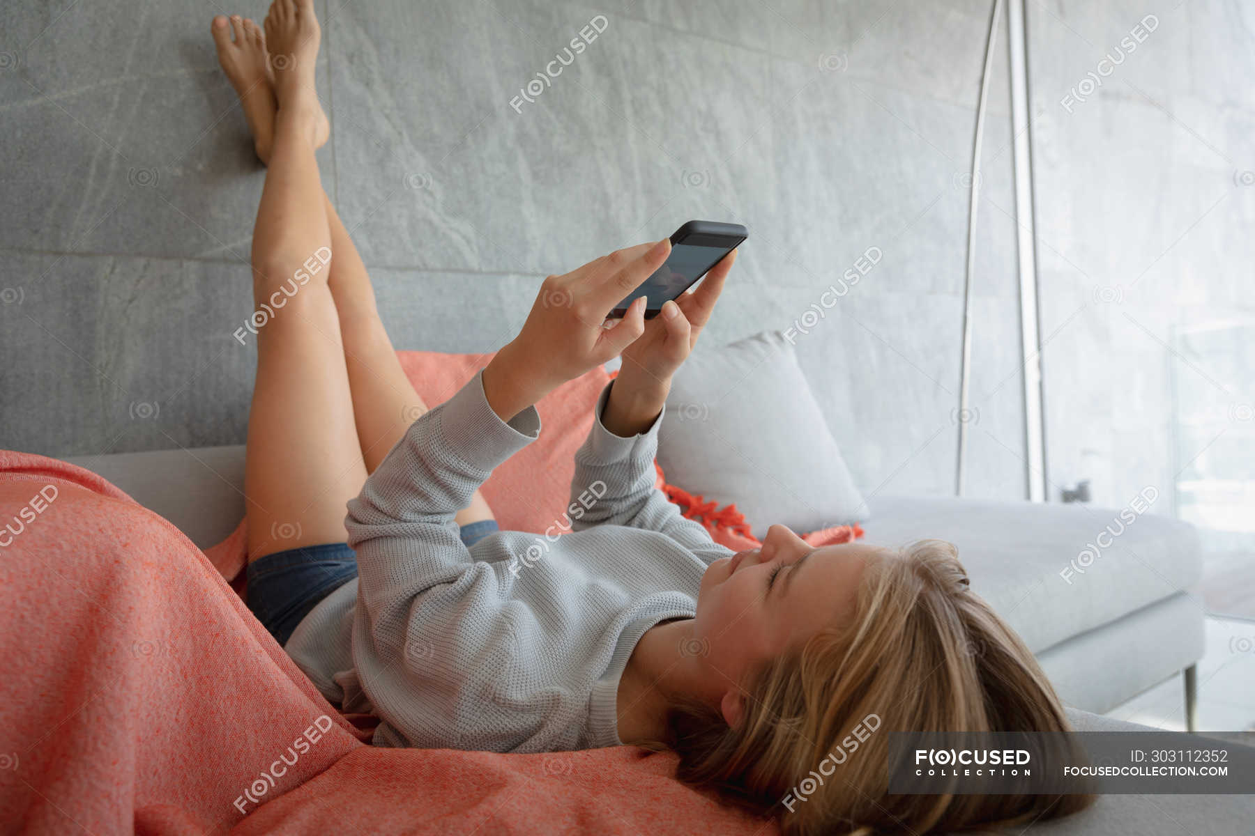 Женщина лежит на диване с поднятыми ногами