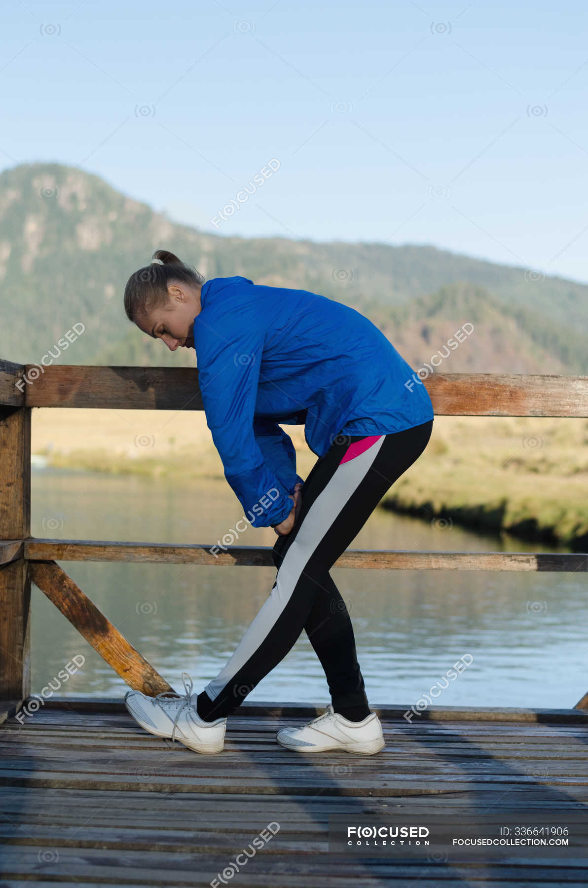 Side view of female athlete exercising on pier against clear sky ...