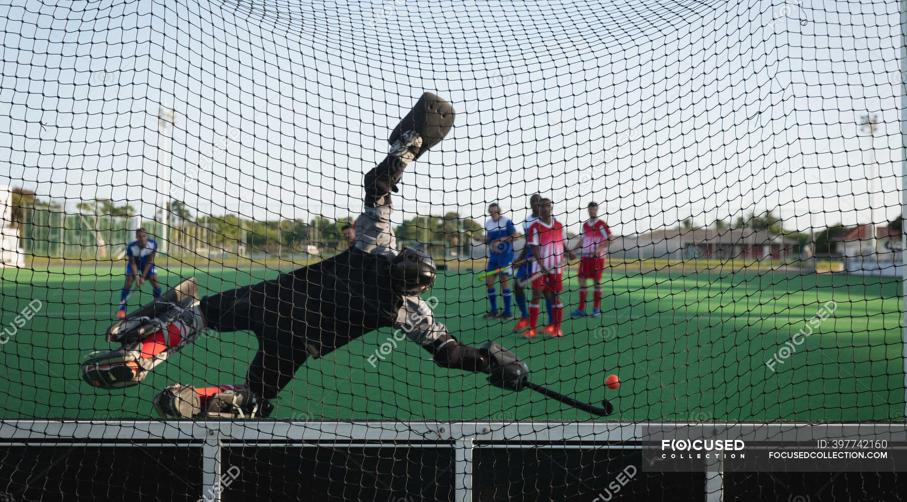 Rear view of a teenage Caucasian male field hockey goalkeeper in action