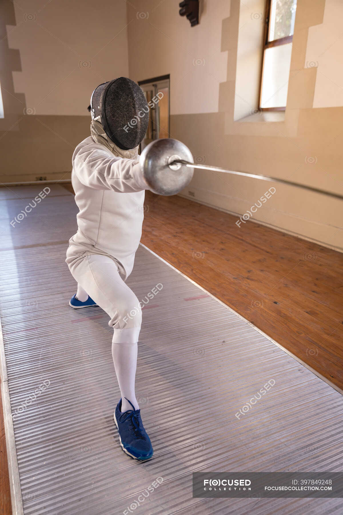 Caucasian sportsman wearing protective fencing outfit during a fencing  training session, preparing for a duel, holding an epee and lunging.  Fencers training at a gym. — power, glove - Stock Photo | #397849248