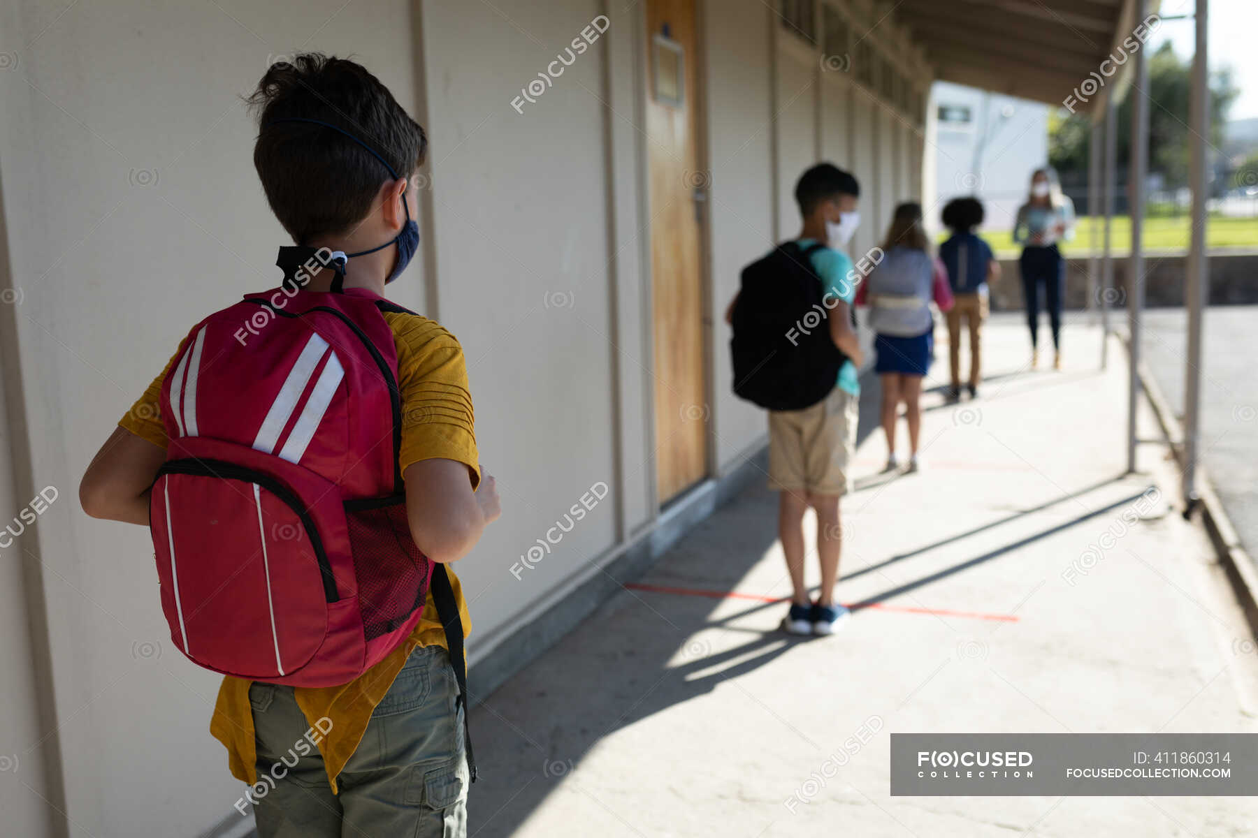 Rear view of a group of children waiting for temperature measure in an ...