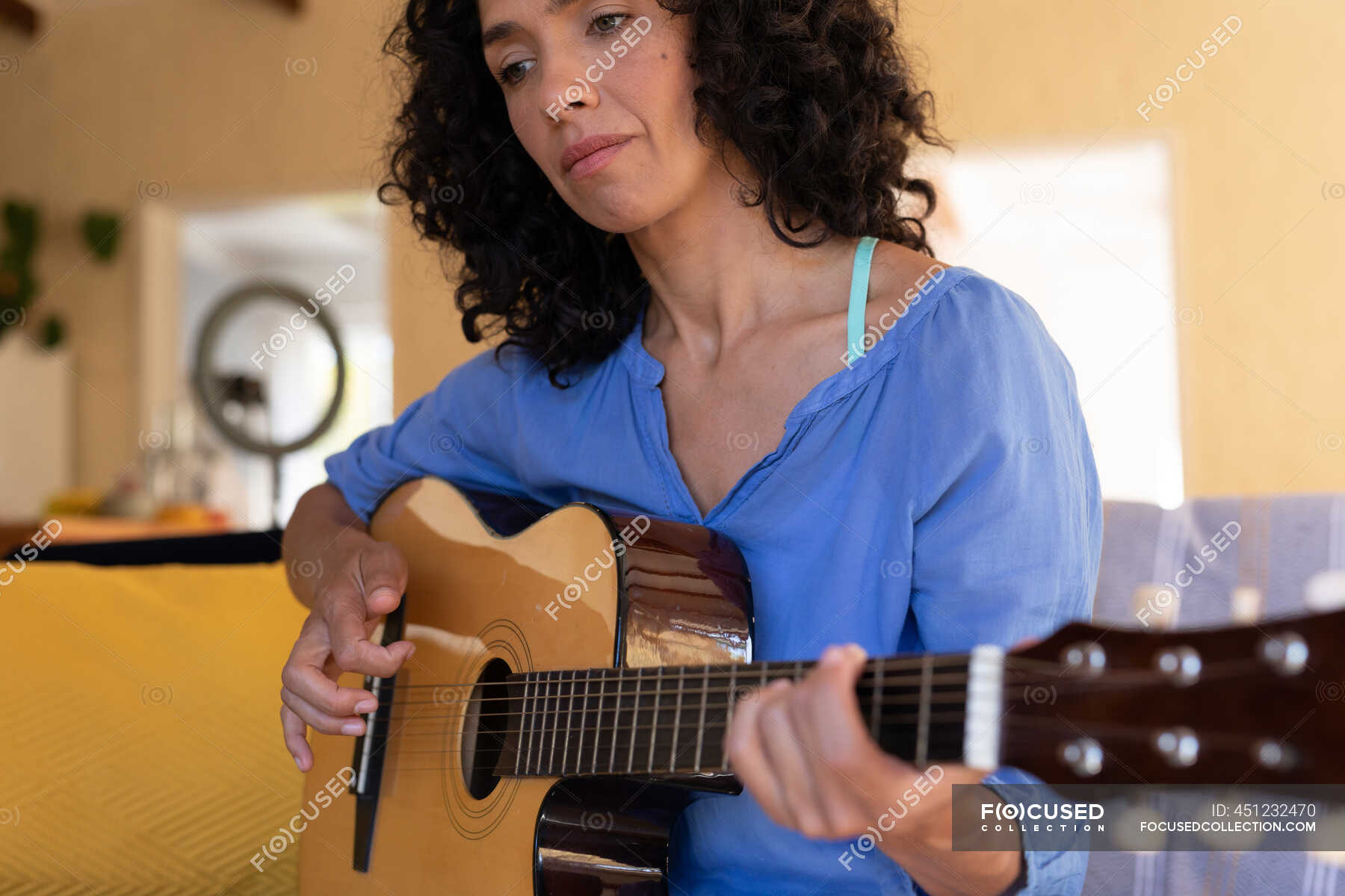 Caucasian woman playing guitar sitting on sofa at home. Staying at home ...