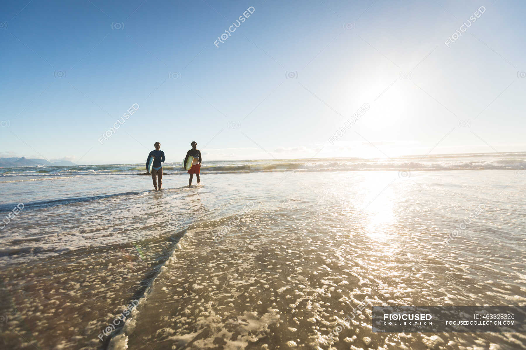 Happy african american couple in the sea carrying surfboards. healthy ...