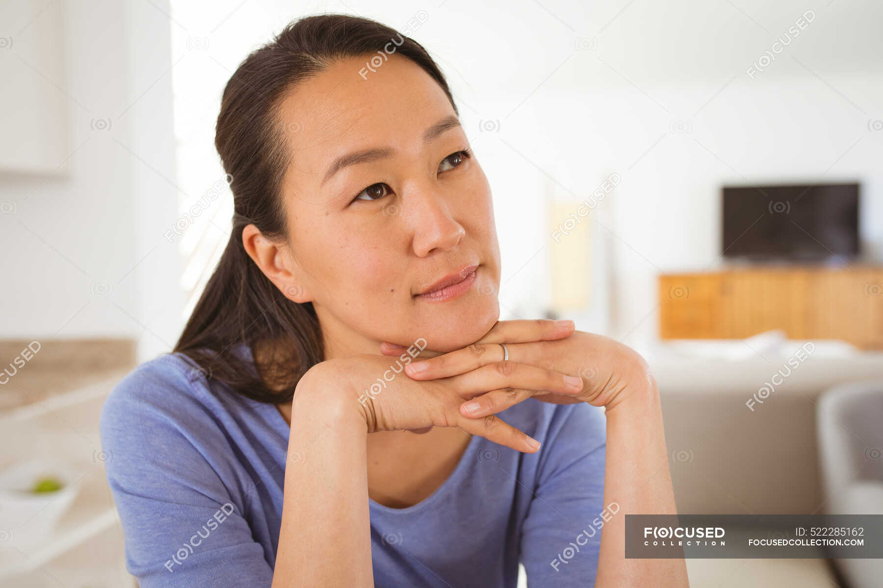 Portrait of thoughtful asian woman sitting at sofa at home. lifestyle ...