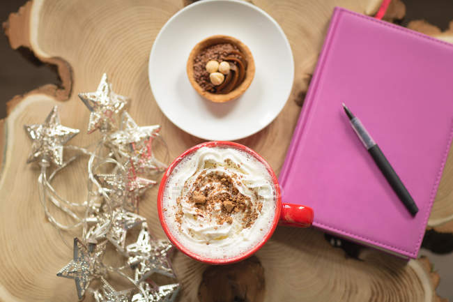 Сладкая еда и дневник с ручкой на столе дома — стоковое фото