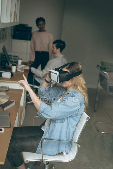 Female executive using virtual reality headset in office — Stock Photo