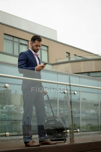 Uomo d'affari che utilizza il telefono cellulare nei locali dell'hotel — Foto stock