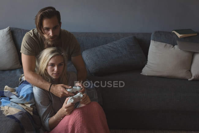 Pareja jugando videojuegos en la sala de estar en casa - foto de stock