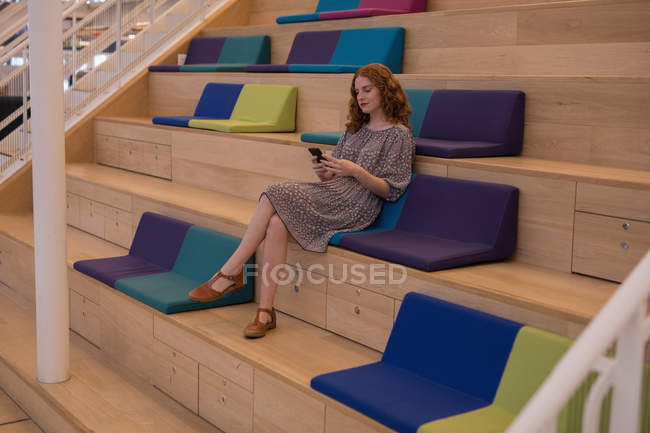 Beautiful female executive using mobile phone in modern office — Stock Photo