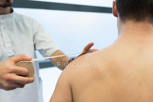 Physiotherapist applying bandage on patients shoulder in clinic — Stock Photo