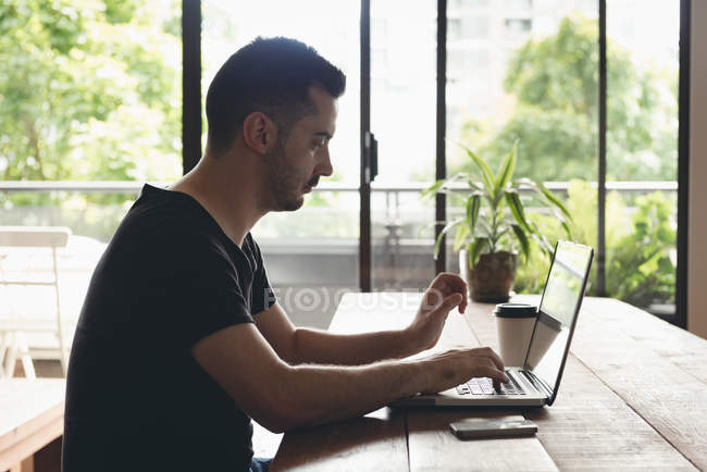 Homme d'affaires utilisant un ordinateur portable à la cafétéria au bureau — Photo de stock