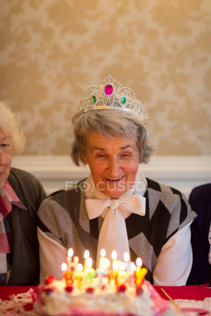 Donna anziana che festeggia il compleanno con i suoi amici a casa — Foto stock
