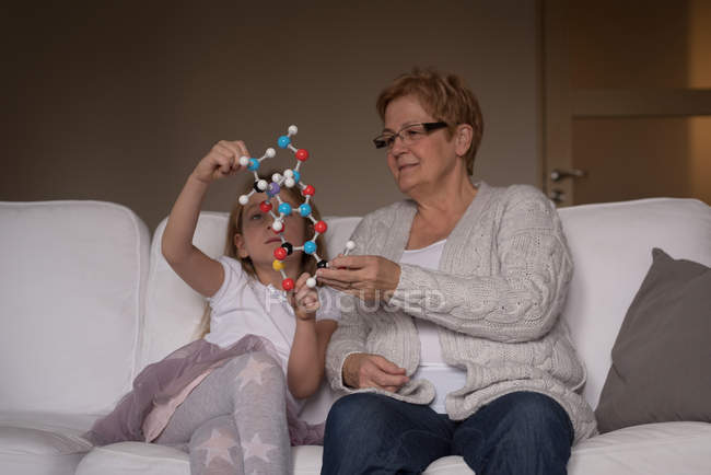 Grand-mère et petite-fille jouent avec le modèle de molécule dans le salon à la maison — Photo de stock