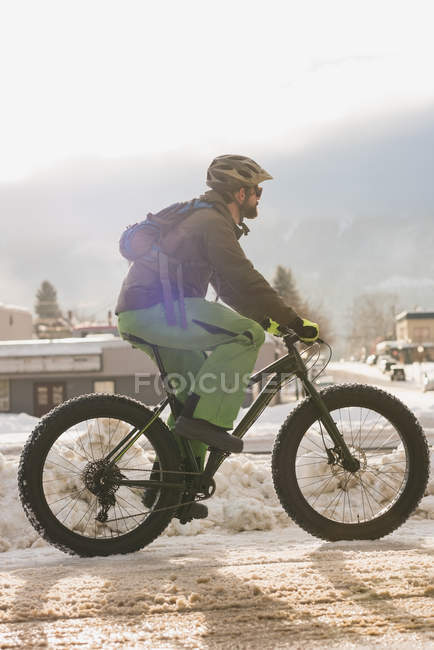 Homem andando de bicicleta na calçada durante o inverno — Fotografia de Stock
