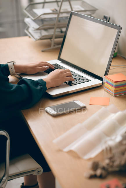Seção intermediária do executivo feminino trabalhando no laptop no escritório — Fotografia de Stock