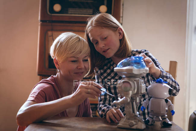 Madre e hija arreglando el juguete robótico en casa - foto de stock