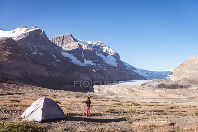 Вид сзади на женщину, стоящую возле палатки в солнечный день — стоковое фото