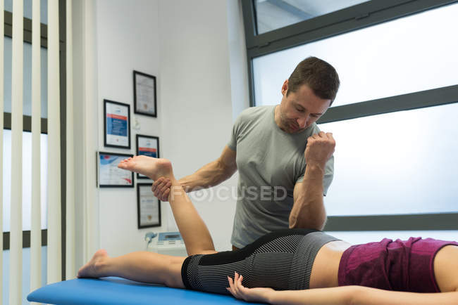 Физиотерапевт, делающий массаж ног женщине в клинике — стоковое фото