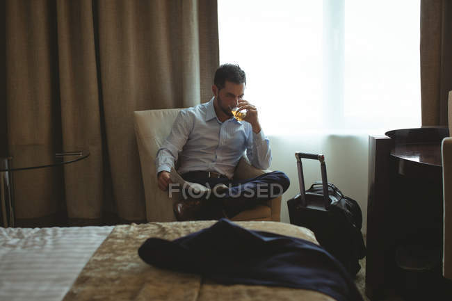 Empresário tomando um copo de uísque no quarto de hotel — Fotografia de Stock