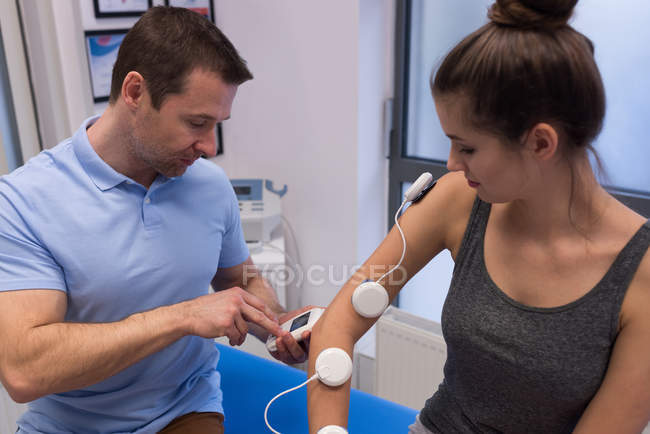 Physiotherapist applying electrode pads on woman's hand in clinic — Stock Photo