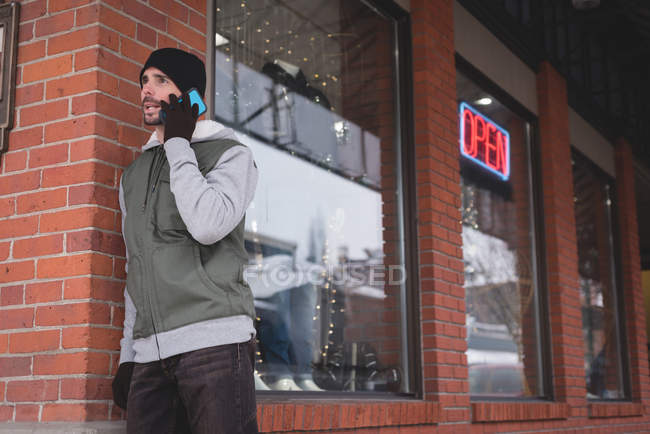Молодой человек разговаривает по мобильному телефону возле магазина — стоковое фото