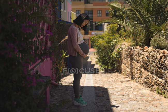 Беременная женщина прикасается к животу на улице — стоковое фото