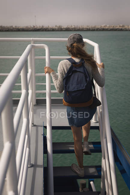 Rear view of woman with backpack climbing staircase of cruise ship — Stock Photo