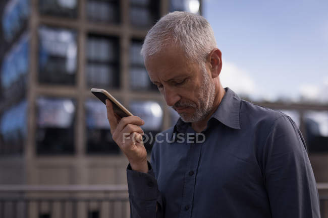Businessman holding mobile phone in hotel premises — Stock Photo