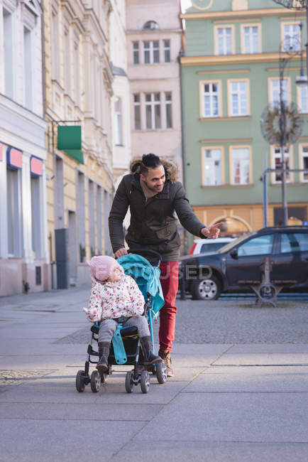 Padre caminando con su hija en la acera en la calle de la ciudad - foto de stock