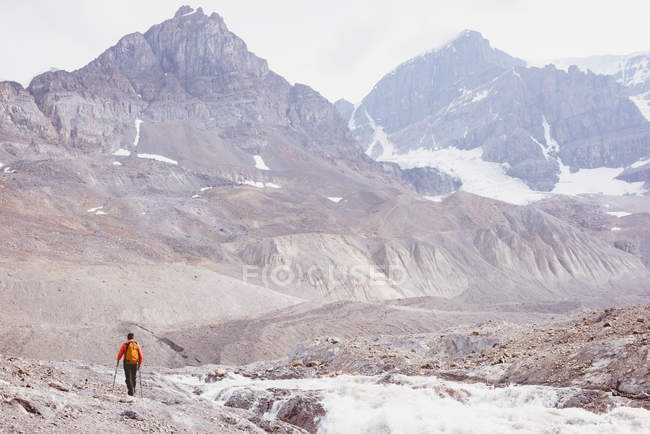 Male hiker with backpack walking near river on a sunny day — Stock Photo