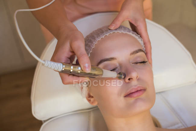 Beautician using a machine on female customer in parlour — Stock Photo