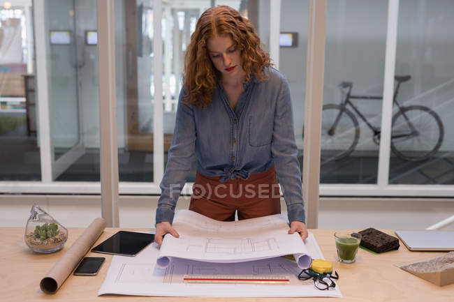 Diseñadora gráfica femenina trabajando en un plano en la oficina - foto de stock
