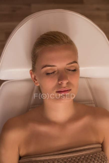 Жінка отримує косметичні процедури, лежачи на ліжку салону у вітальні — стокове фото