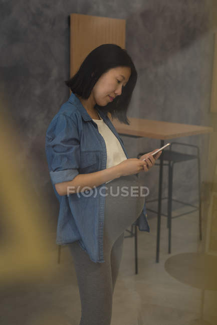 Вагітна бізнес-леді використовує мобільний телефон в офісі — стокове фото