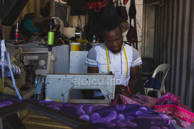 Tailor sewing clothes on sewing machine at shop — Stock Photo