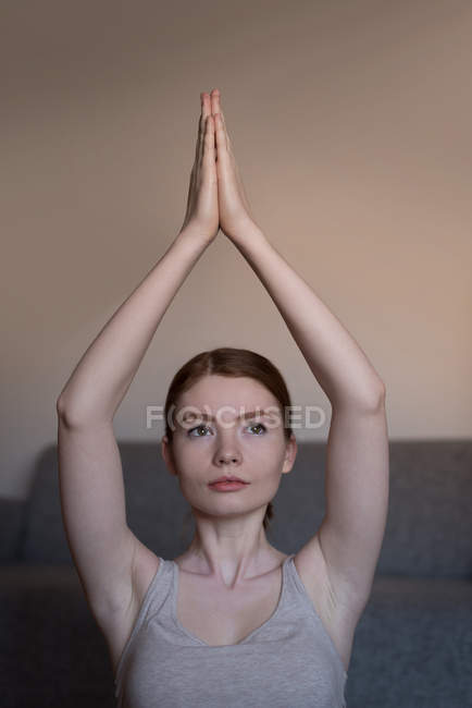 Retrato de una joven practicando yoga en la sala de estar - foto de stock