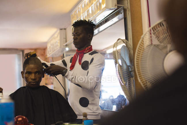 Barber coupe les cheveux du client dans le salon de coiffure — Photo de stock