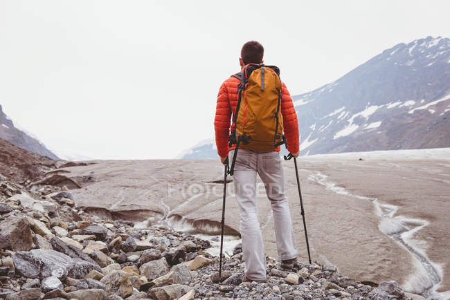 Vista posteriore dell'escursionista in piedi con zaino in una giornata di sole — Foto stock