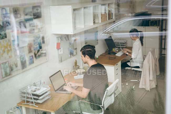 Виконавці використовують ноутбук і мобільний телефон за столом в офісі — стокове фото
