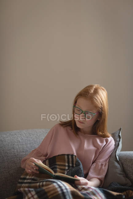 Дівчина читає книгу у вітальні вдома — стокове фото