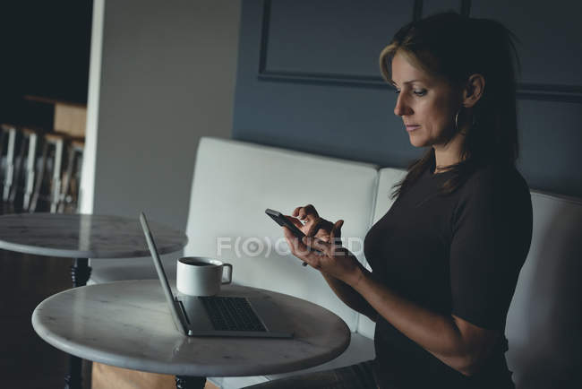 Бізнес-леді за допомогою мобільного телефону в кафетерії в офісі — стокове фото