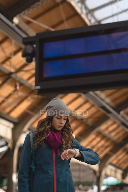Молода жінка перевіряє час на смарт-годиннику на залізничній станції — стокове фото