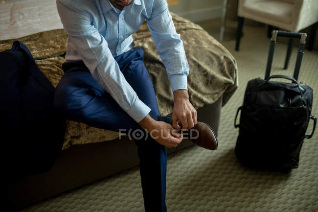 Empresário amarrando sapatos cadarços no quarto de hotel — Fotografia de Stock