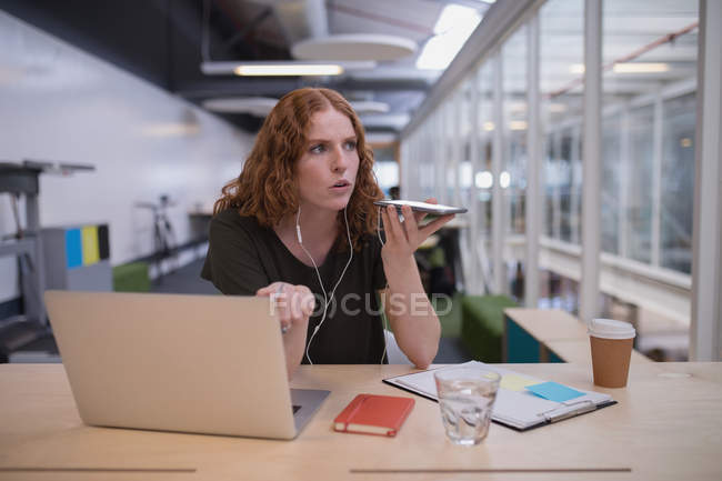 Executivo feminino falando no telefone celular na mesa no escritório — Fotografia de Stock