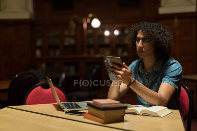 Jovem usando tablet digital na biblioteca — Fotografia de Stock