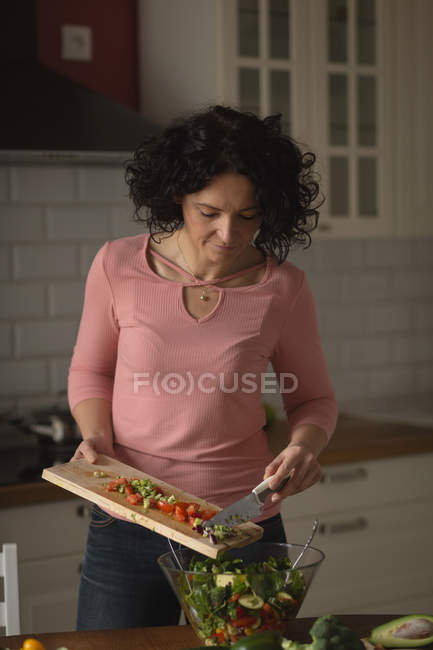 Woman preparing vegetable salad in kitchen at home — Stock Photo