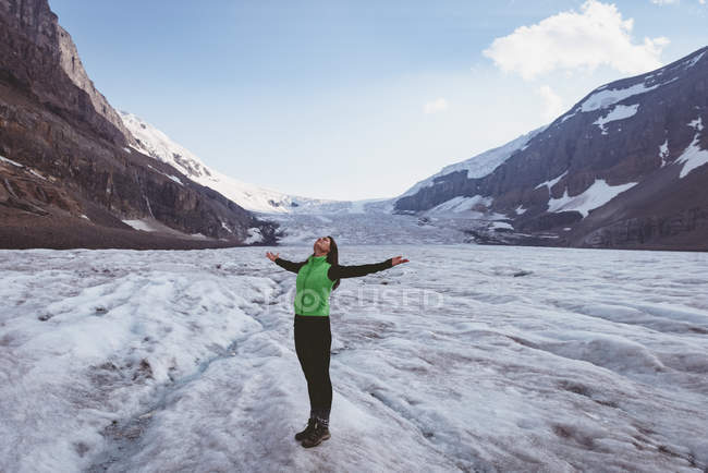 Femme debout avec les bras tendus par une journée ensoleillée pendant l'hiver — Photo de stock