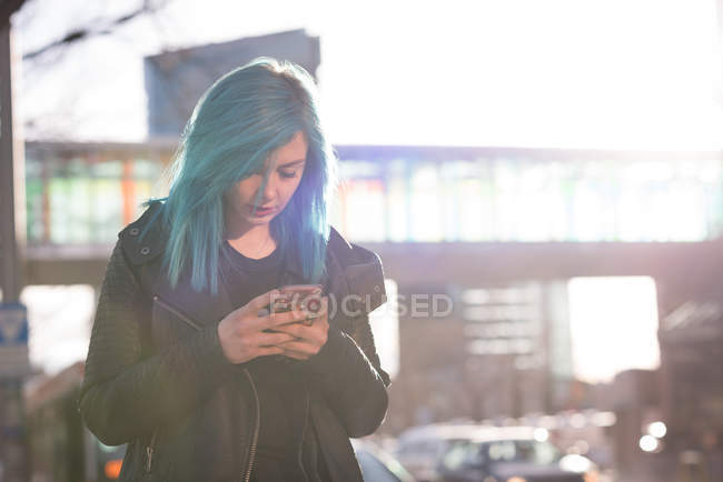 Стильна жінка використовує мобільний телефон в сонячний день — стокове фото
