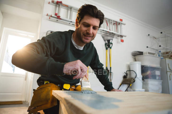 Macho carpinteiro pintando uma mesa na oficina — Fotografia de Stock