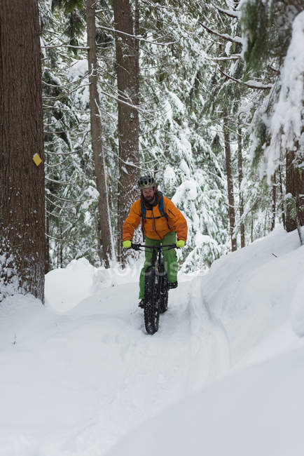 Homem andando de bicicleta em uma paisagem nevada durante o inverno — Fotografia de Stock